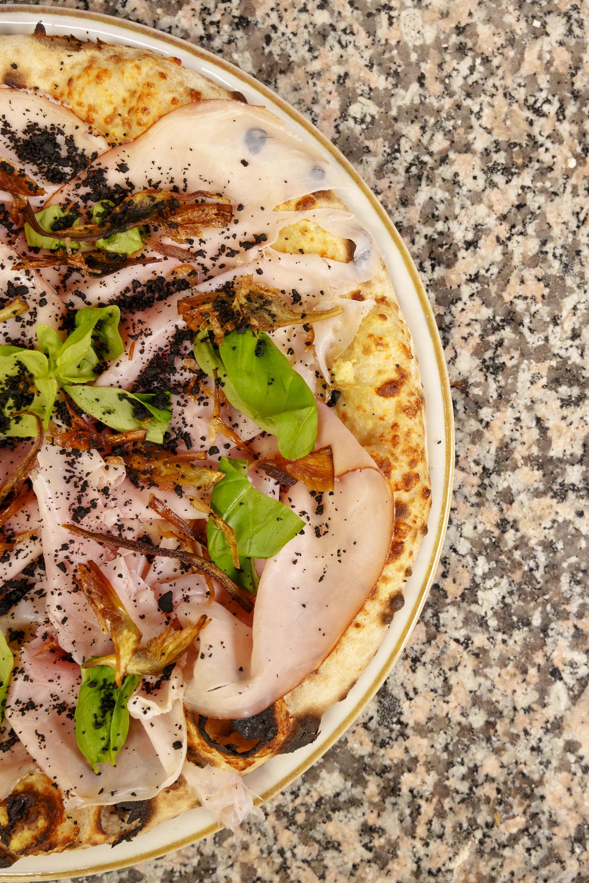Pizza gourmet con prosciutto cotto alla brace, basilico e crumble, vista dall'alto